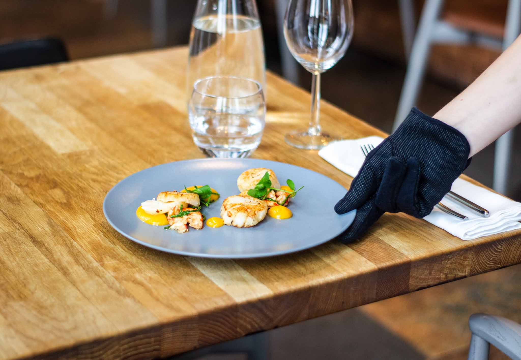 A waitress' hand putting a dish plate on the table in a restaurant