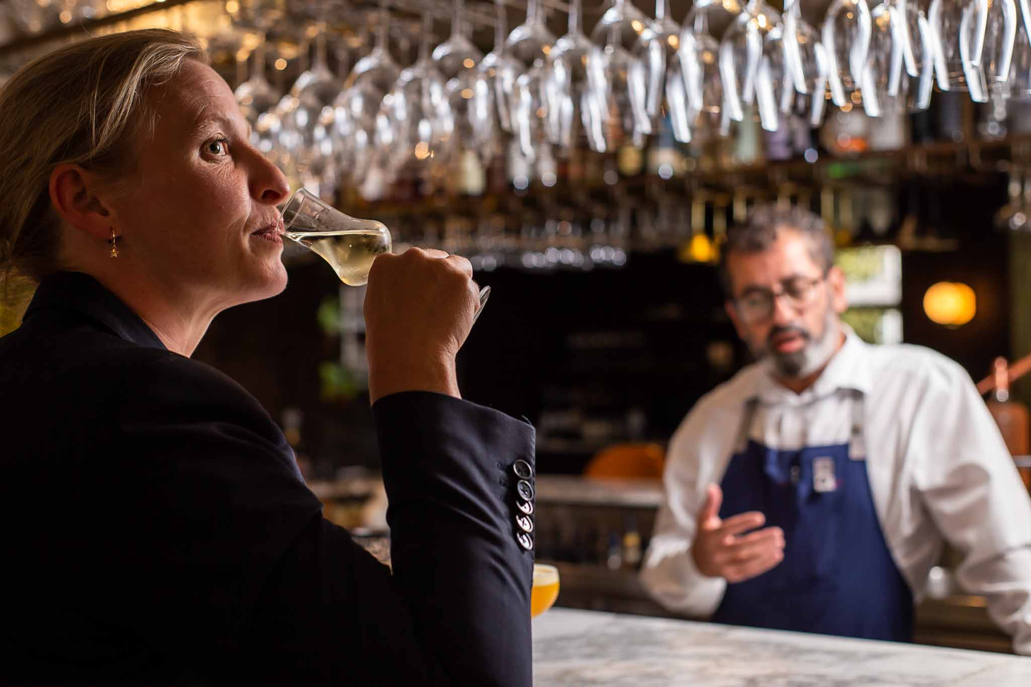 A woman tasting a delicious cocktail in a french restaurant. Photo by restaurant photographer Louis Hansel.