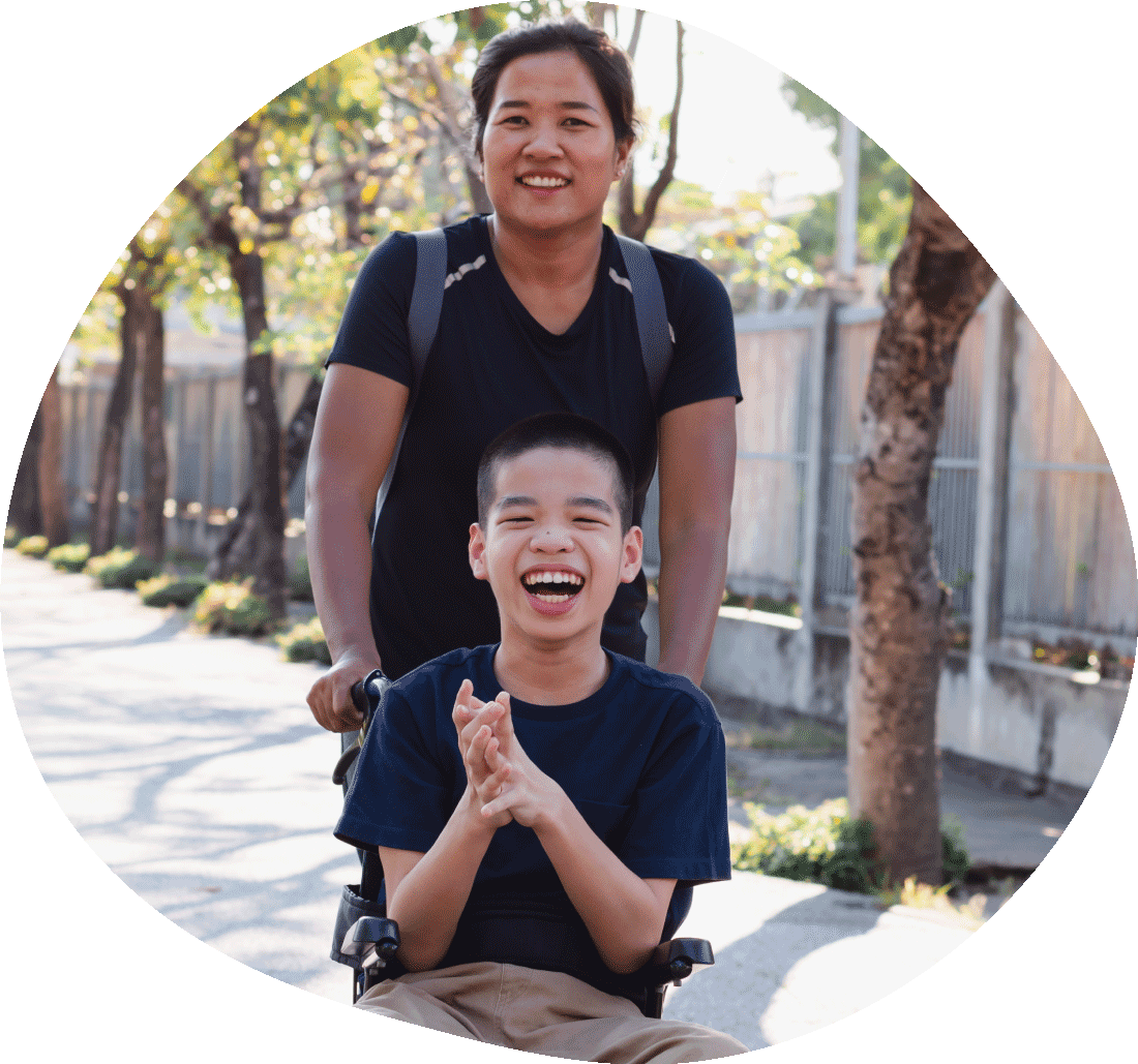 young female carer assists disabled boy in wheelchair