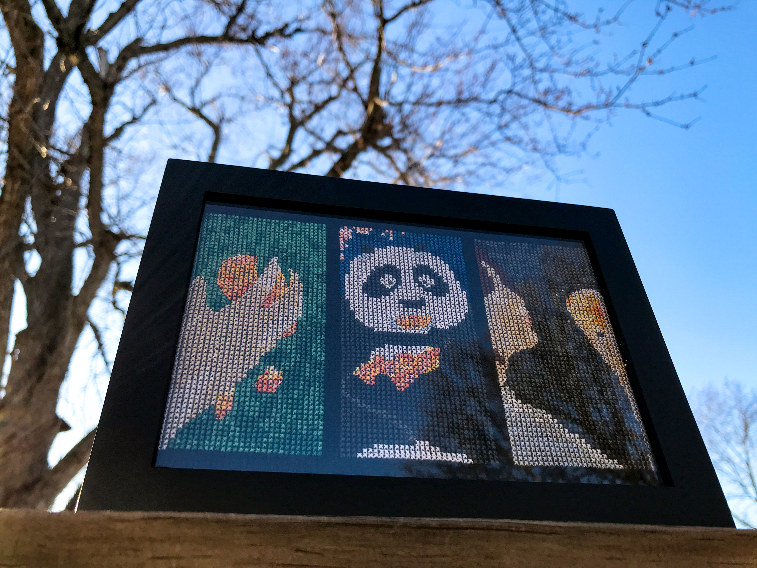 Framed cross stitch depicting three film scenes