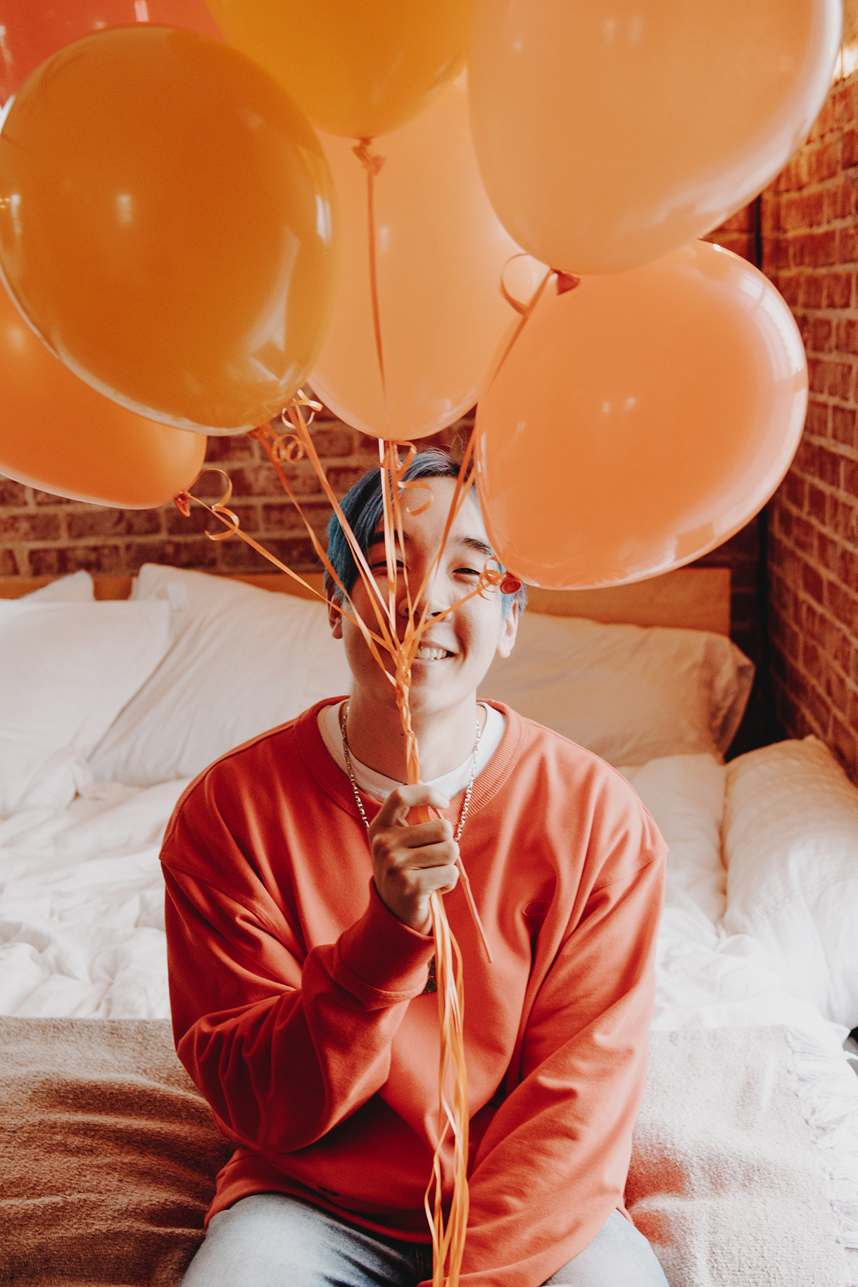 Chow Mane is holding balloons and smiling. 