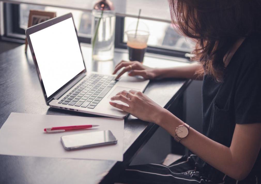 A woman is sitting down at a table with her laptop.