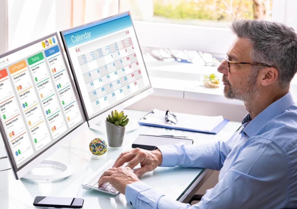 A man is overlooking his calendar on his computer and seeing what tasks he needs to work on.
