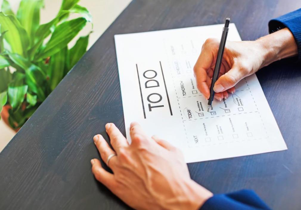 A person sitting at a desk is marking things off of their to-do list.