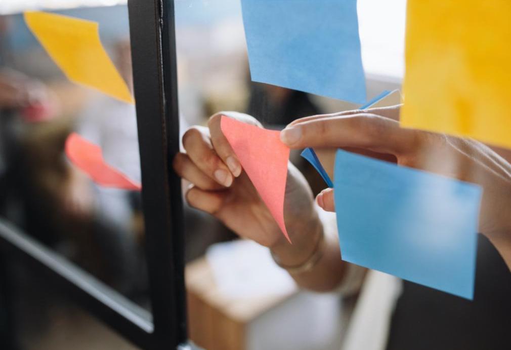 Post-it notes are put onto a glass wall.