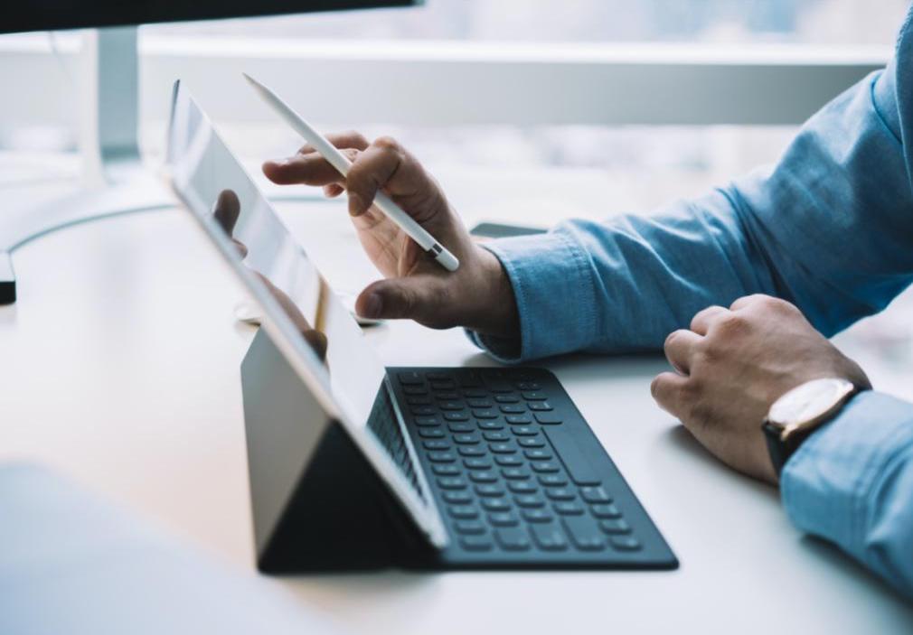 A man is working on his tablet at his desk.