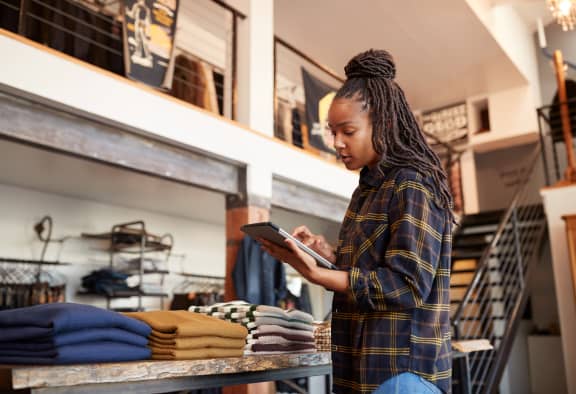 Woman Checking Stock In Retail Store With Tablet