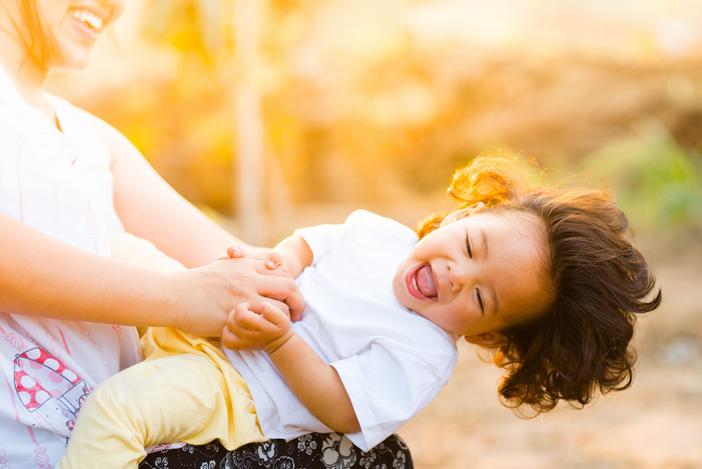 babysitter playing with a toddler both laughing