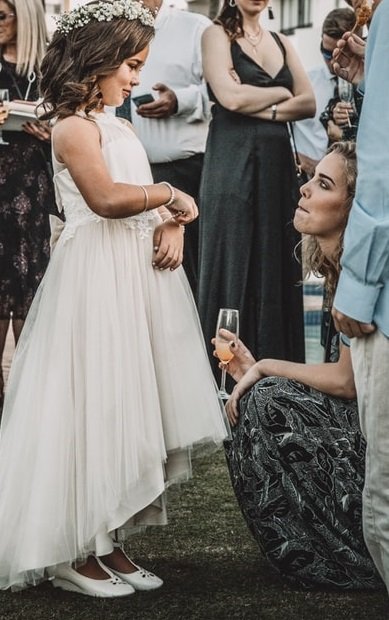 flower girl at wedding reception attending to crouching bridesmaid.