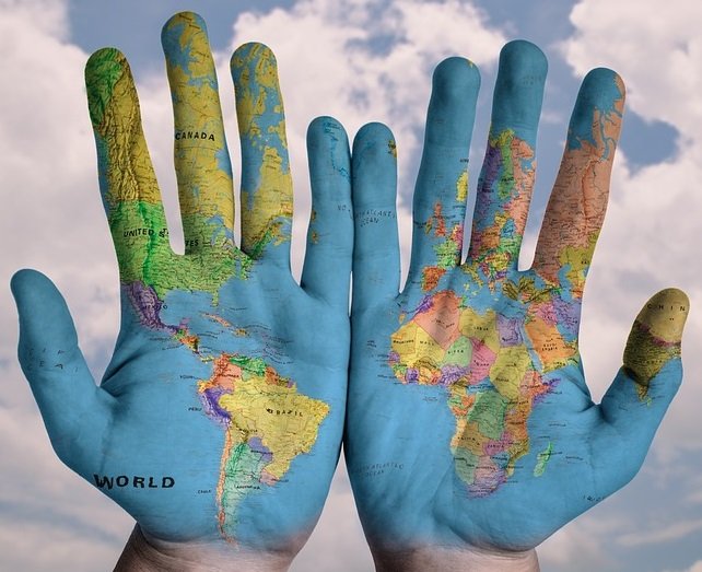 two hands spread painted with image of world map showing Americas and Europe and Africa.