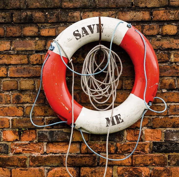 red and white rescue life ring hanging on a brick wall letters SAVE ME.