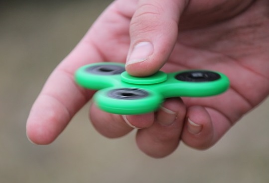 hand holding a green fidget spinner
