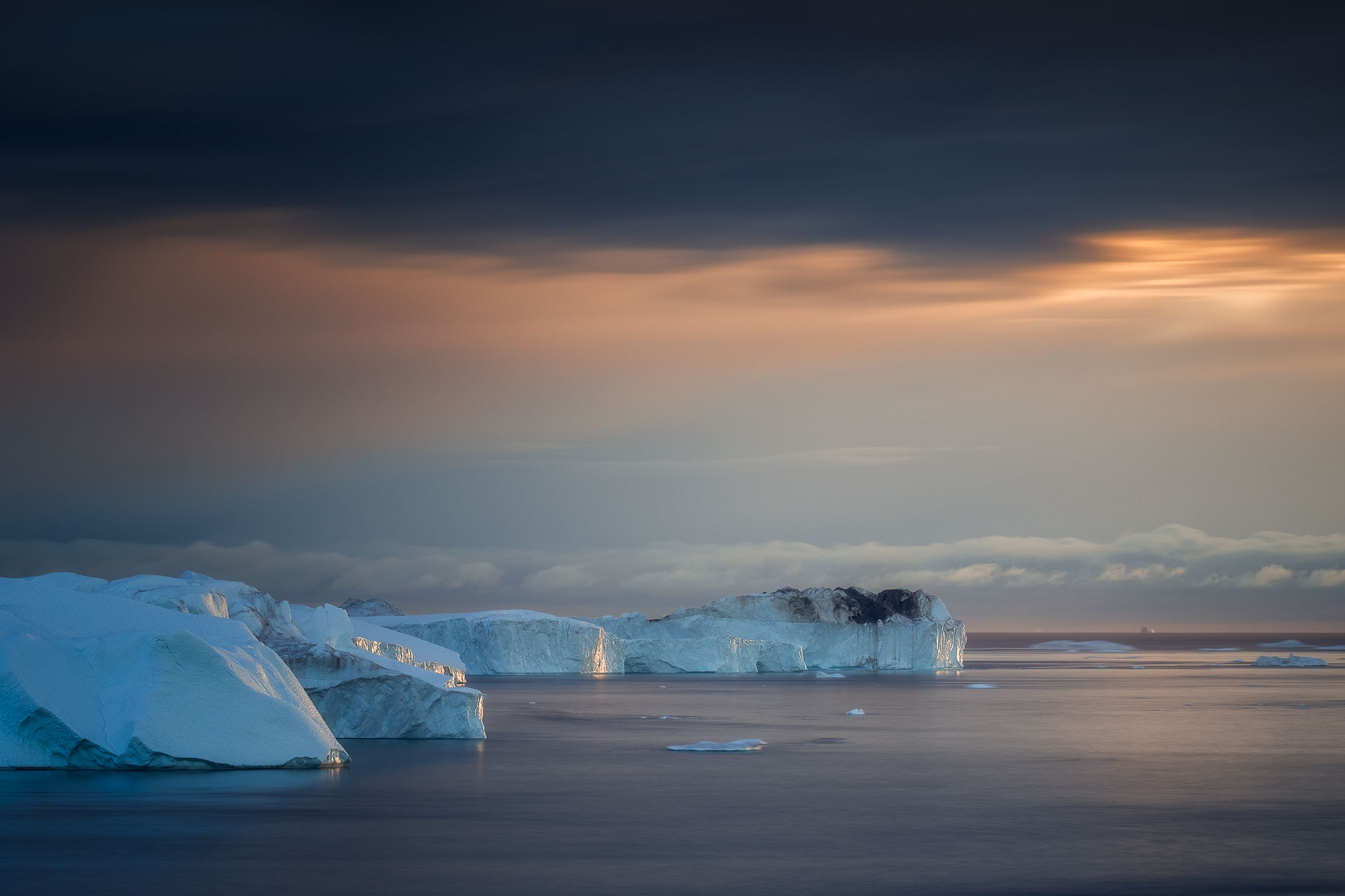 Golden hour over the sea with icebergs in the foreground