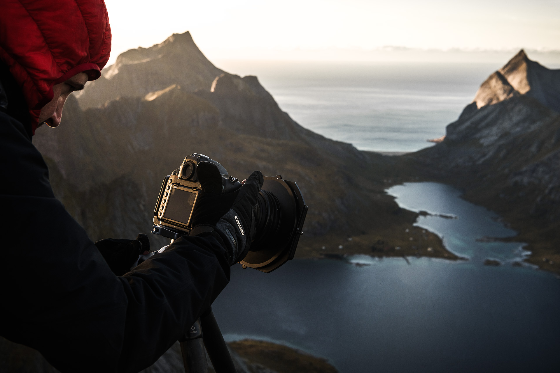 Photographer looking at the LCD view of their camera with a mountain landscape in the background
