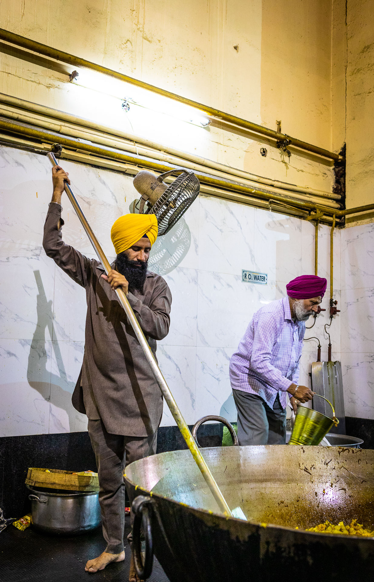 Two men cooking with a large skillet, India