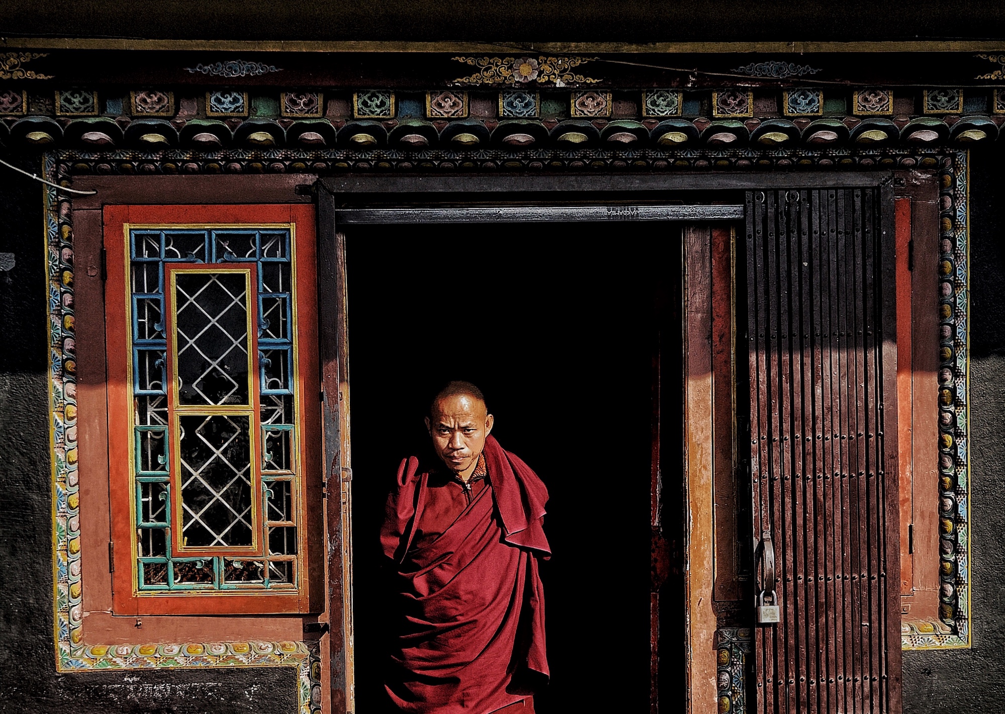 Buddhist monk standing in front of the colourful door