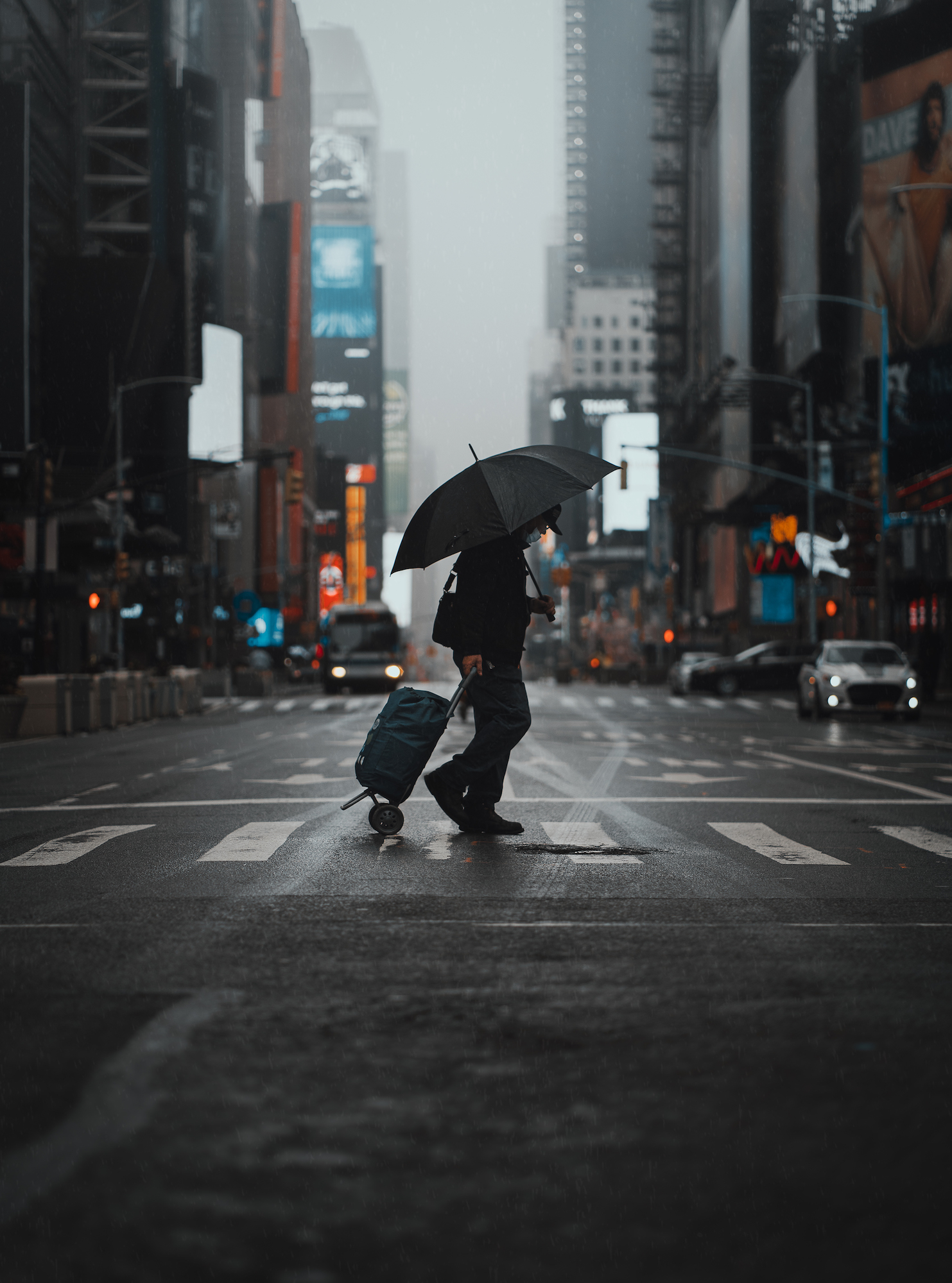 Person with umbrella walking across the street during lockdown in New York