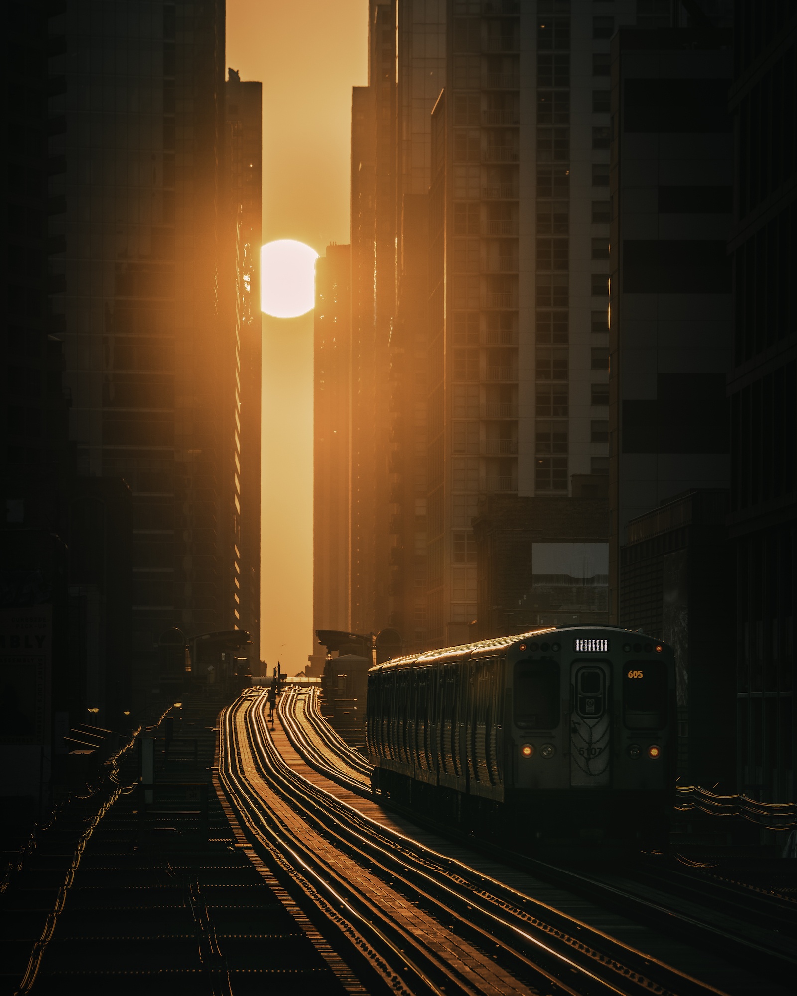 A train makes its way between towering buildings in the golden light of the sun, Chicago, USA