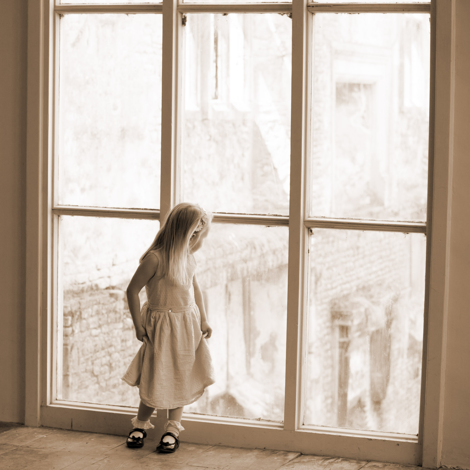 Little girl looking out of a large window
