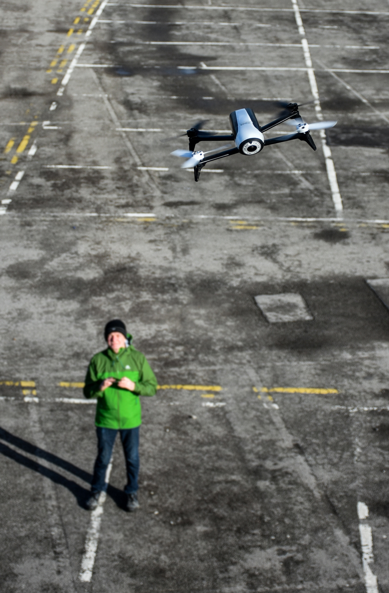Man in a green coat flying a drone