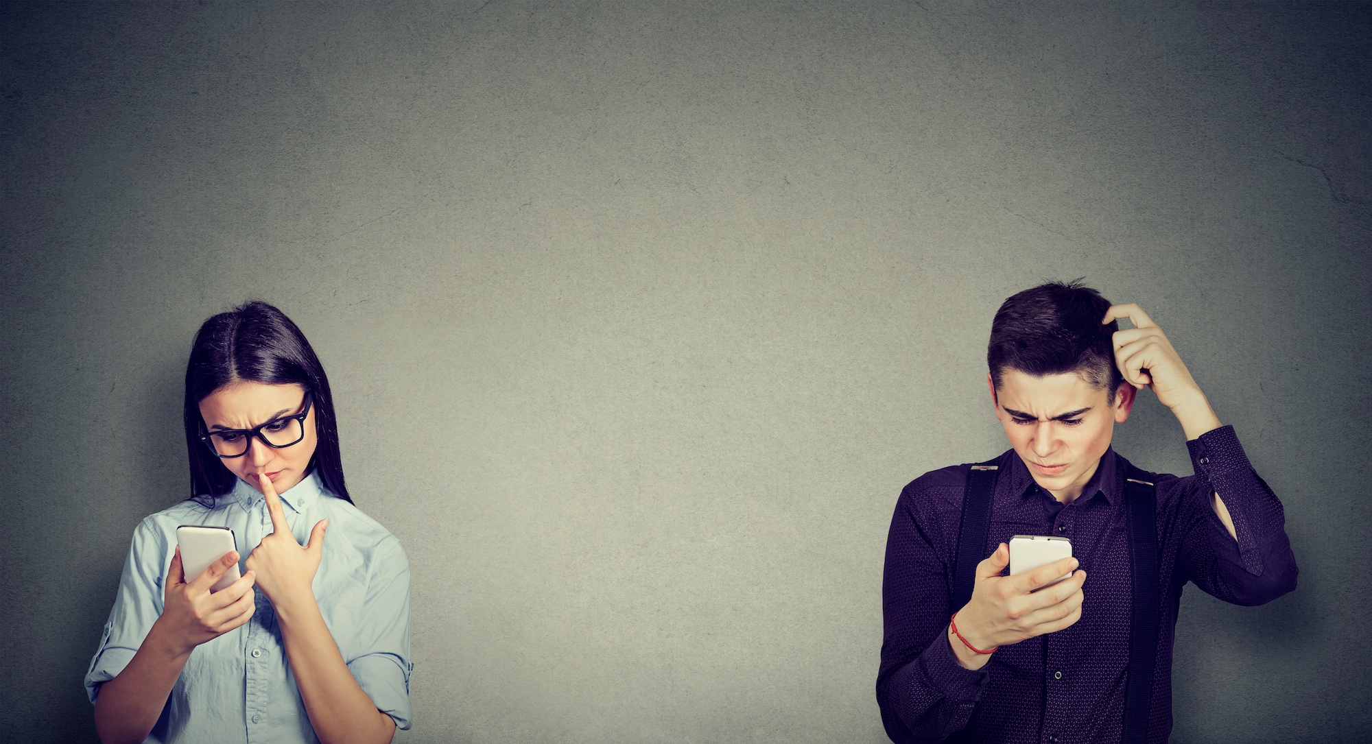 Two people looking at their phones bemused
