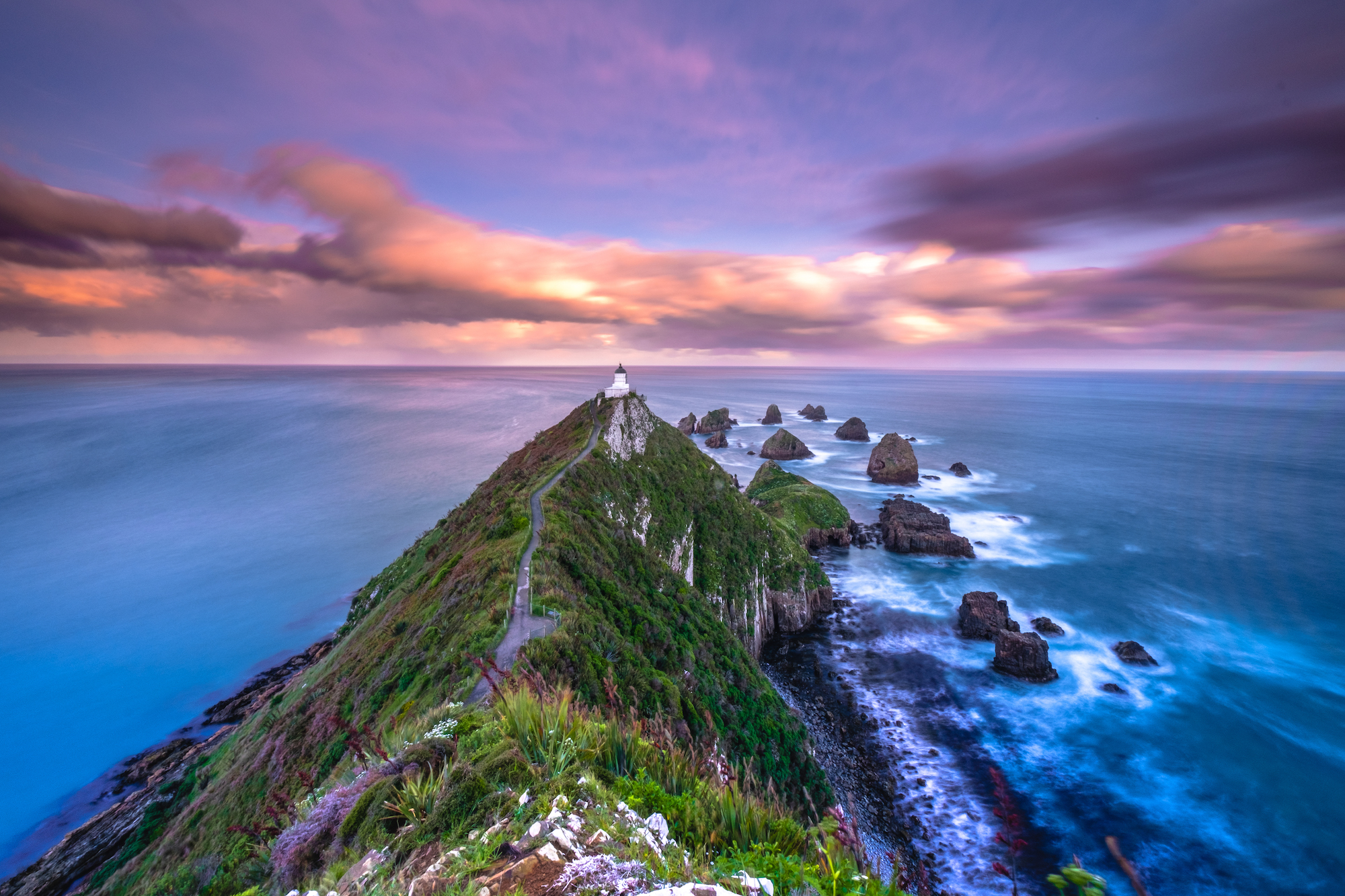 Colourful sunset at Nugget Point lighthouse; Otago, New Zealand