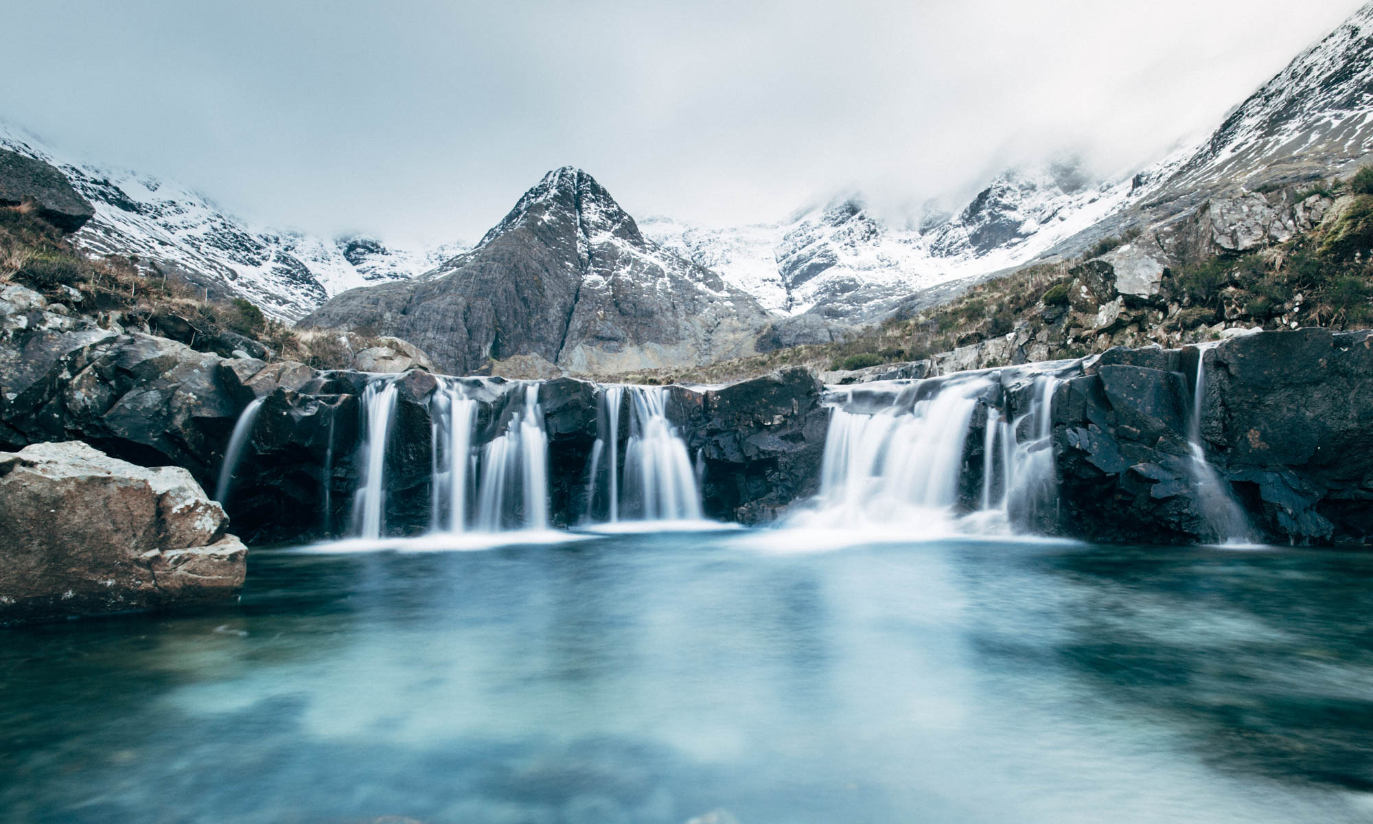 Snow melt trickles down into the blue-tinged 'Fairy Pools' on the Isle of Skye