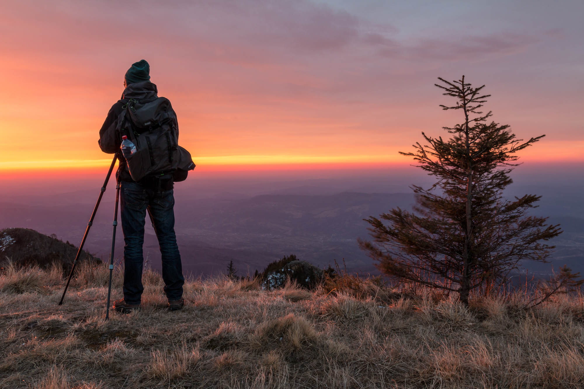 A photographer setting up the frame and capturing a sunrise in the Cozia Mountains, Romania
