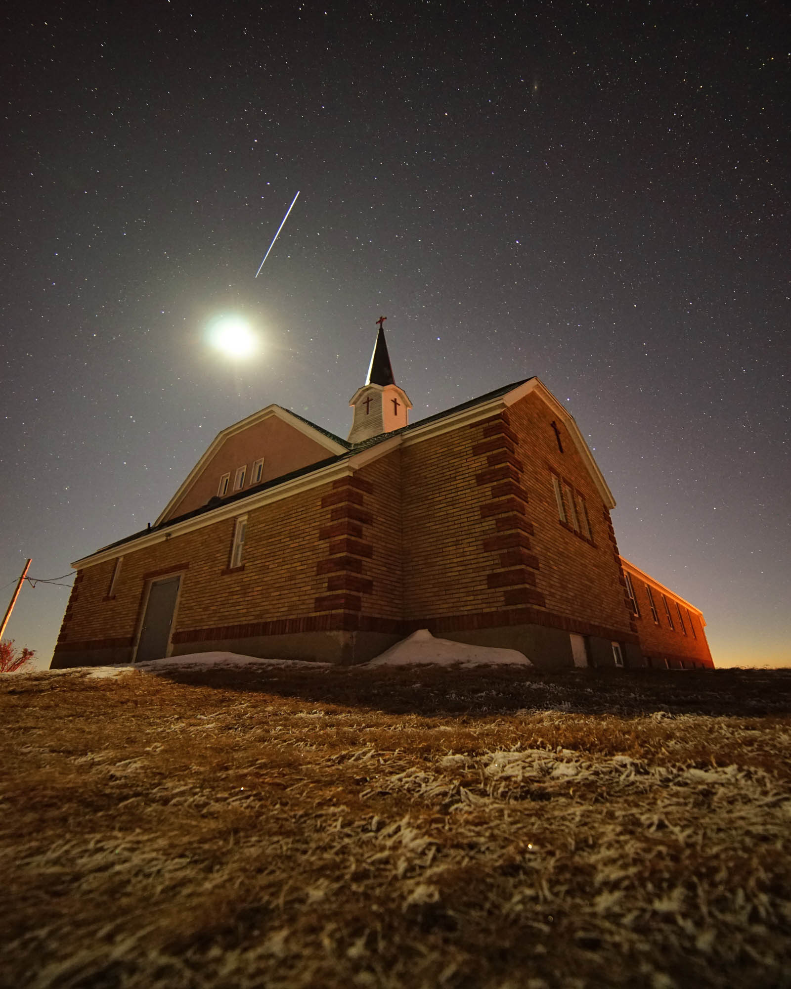 St. Vincents Catholic Church, rural Morton County, North Dakota. Moon above, with international space station flying over.
