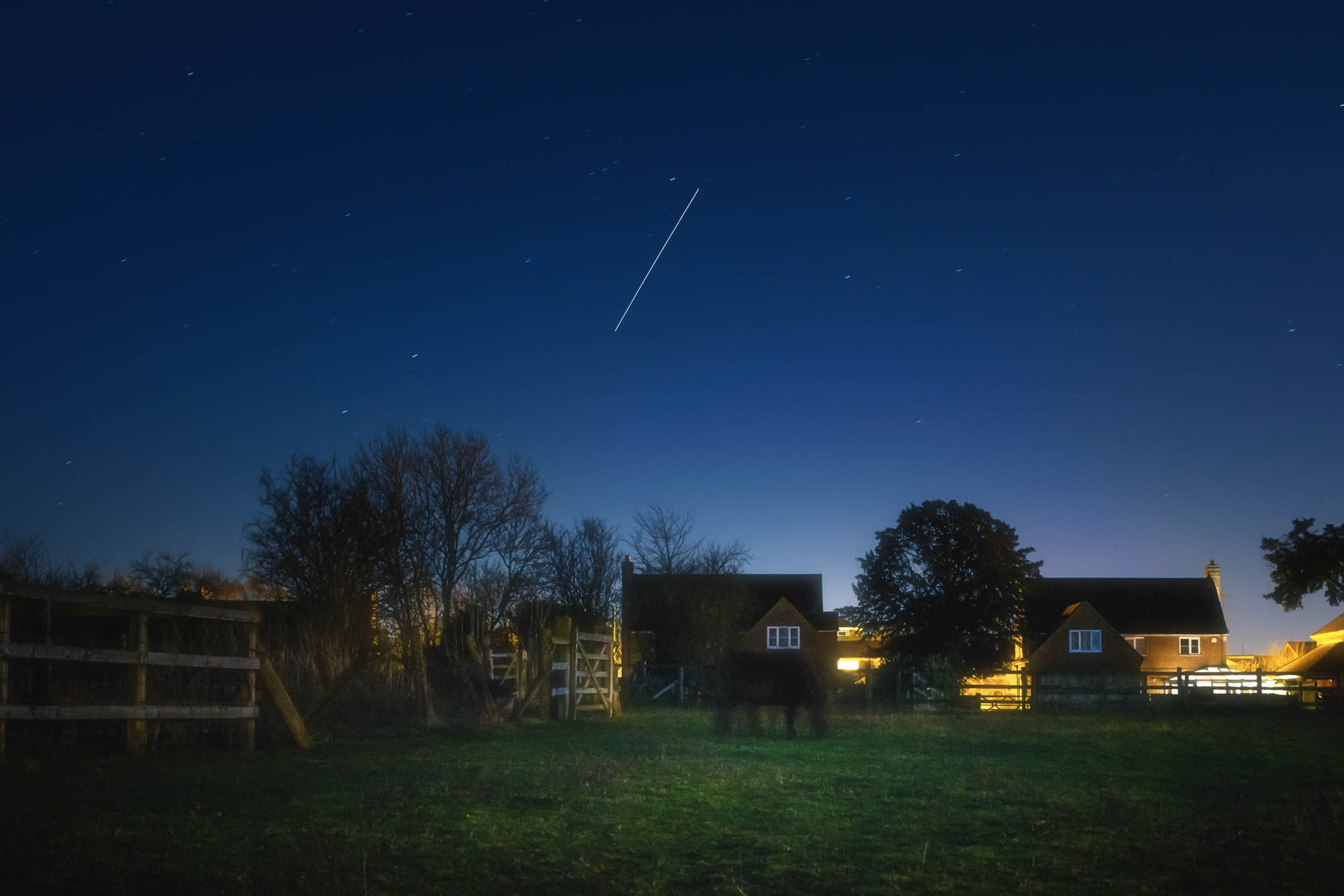 Space station captured over a suburban landscape during the blue hour