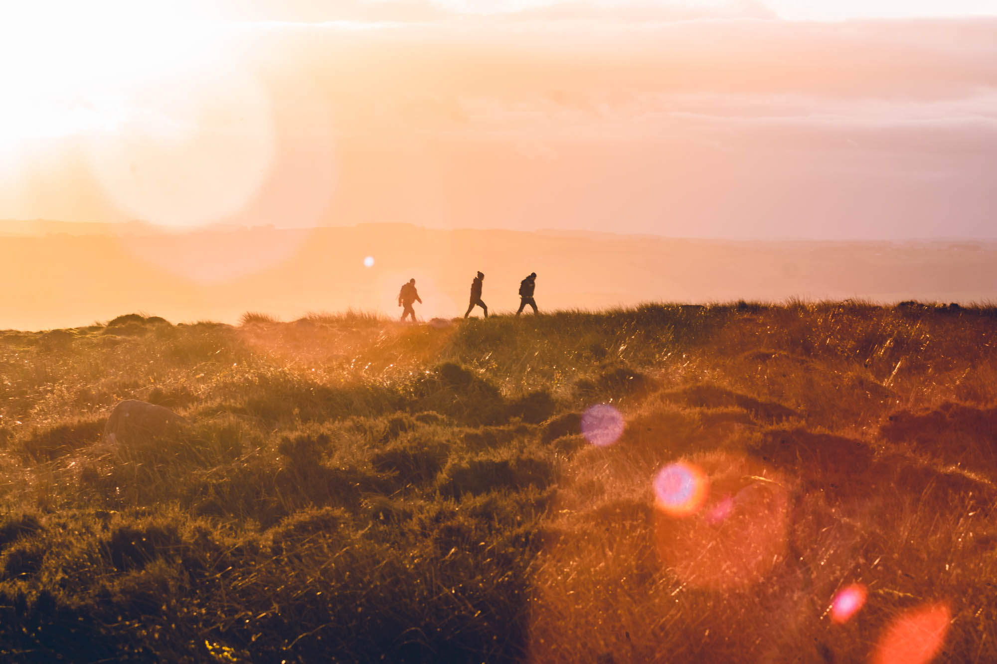 The sun going down a top Curbar Edge, Derbyshire, with lens flare across the scene.