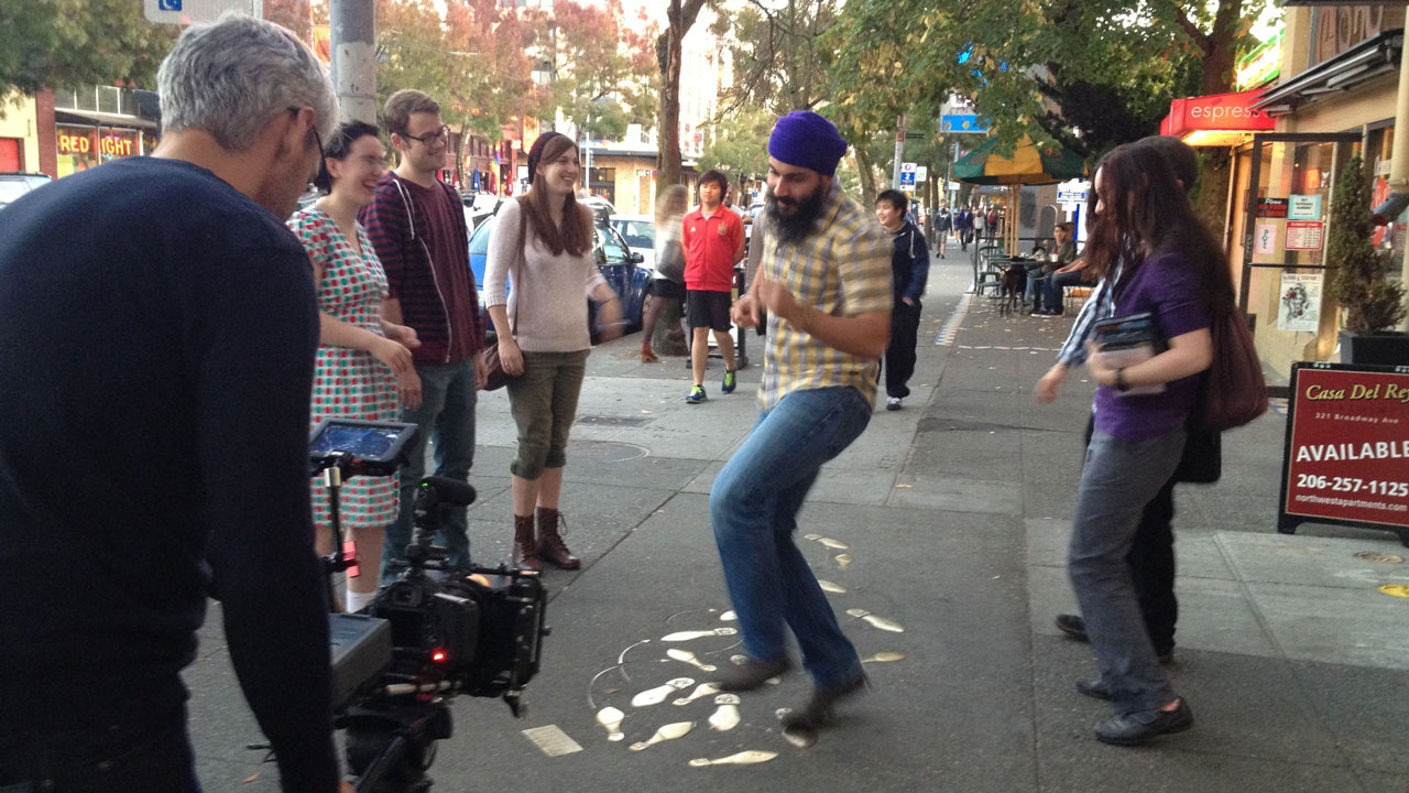 Passerby watch as a person interacts with a street installation in Capitol Hill, Seattle. 