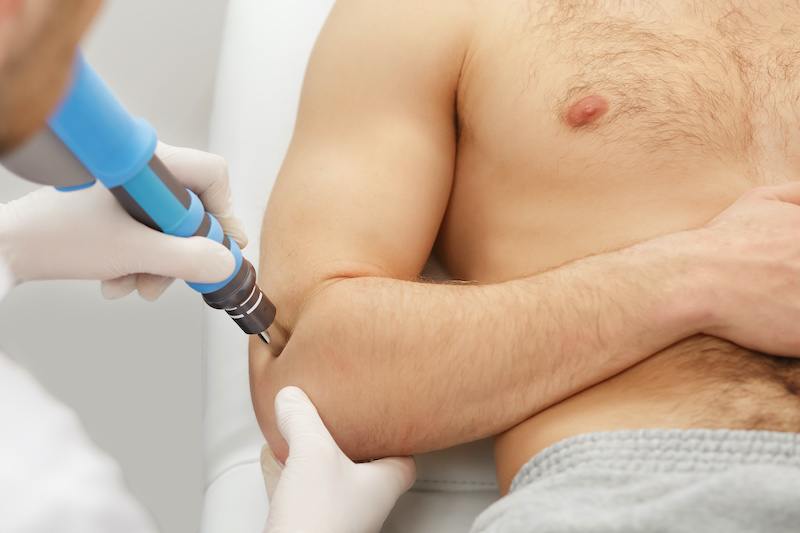 man getting shockwave therapy on elbow