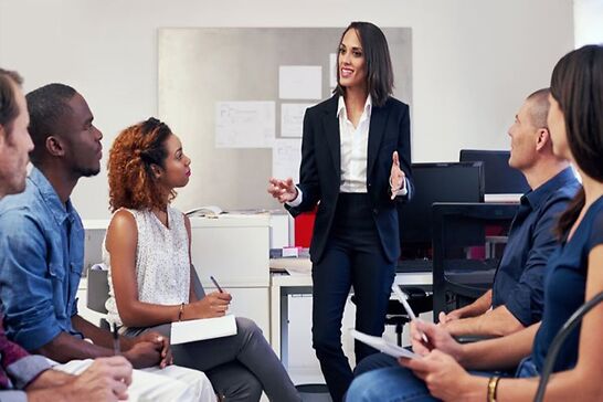 A woman talking to a group of seated people.