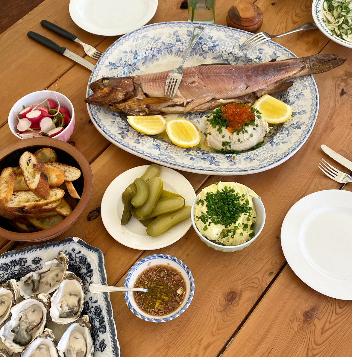 A table hosting a feast of seafood, bread, oysters, dips, salads and cutlery