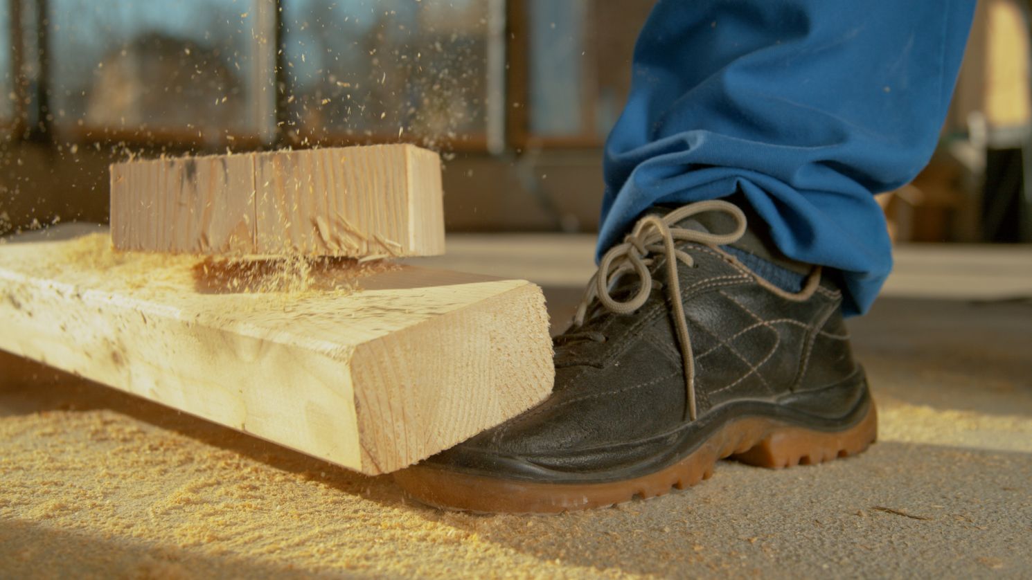 Madera cayendo en un pie de trabajador de construcción.