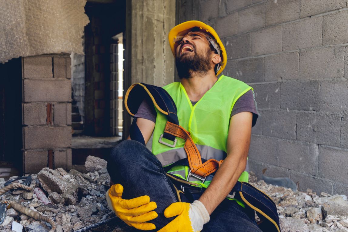 Trabajador de construcción lesionado en la pierna en una obra de construcción.