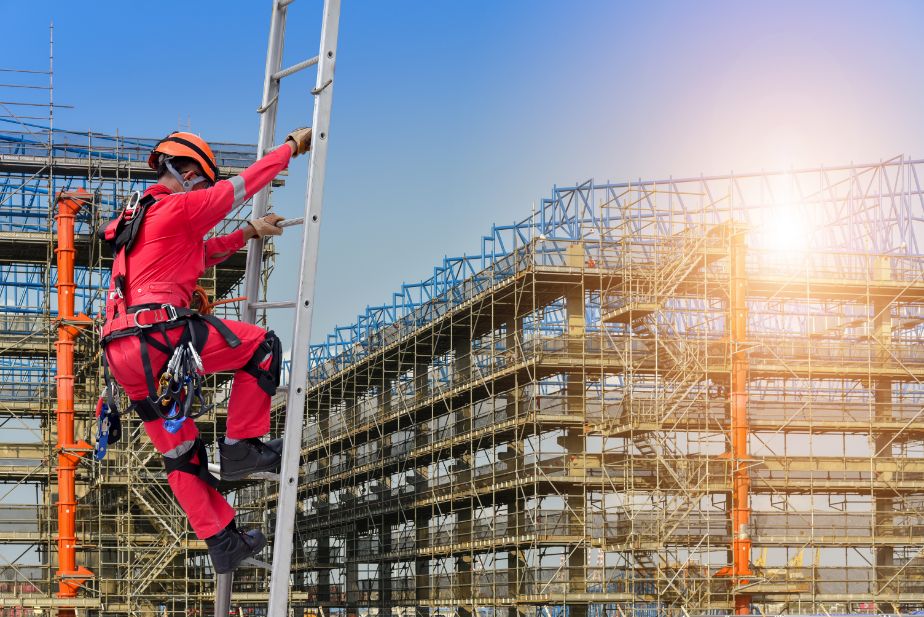 Trabajador subiendo escalera en obra de construcción.
