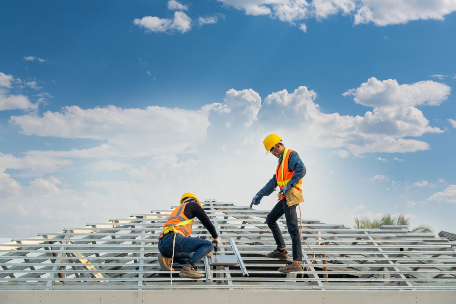Two construction workers installing panels on a roof.