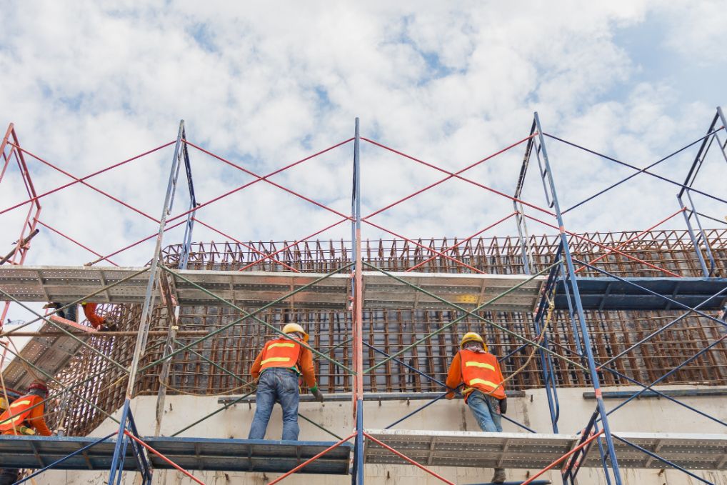 Trabajadores de construcción en un andamio construyendo una pared.