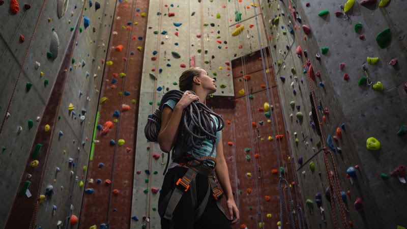 Jovem mulher se preparando para escalar uma parede.