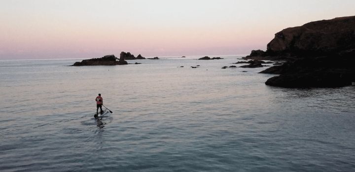 A man paddle boarding at sunset