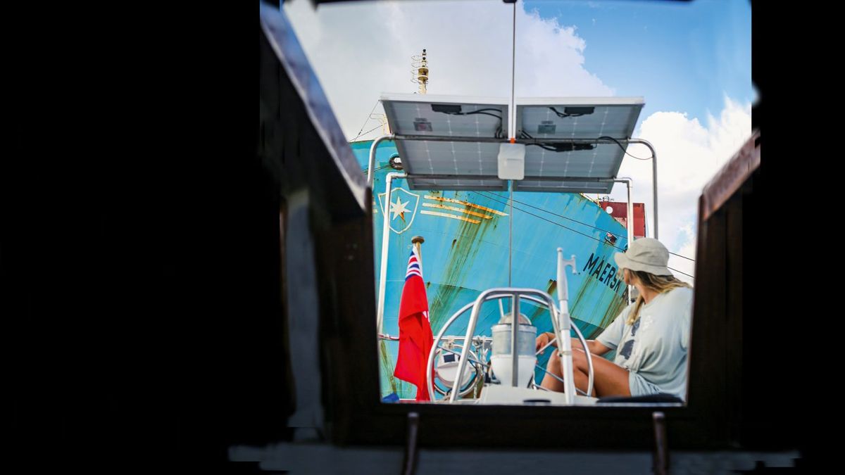 A woman driving a boat through the panama canal followed by a tanker vessel
