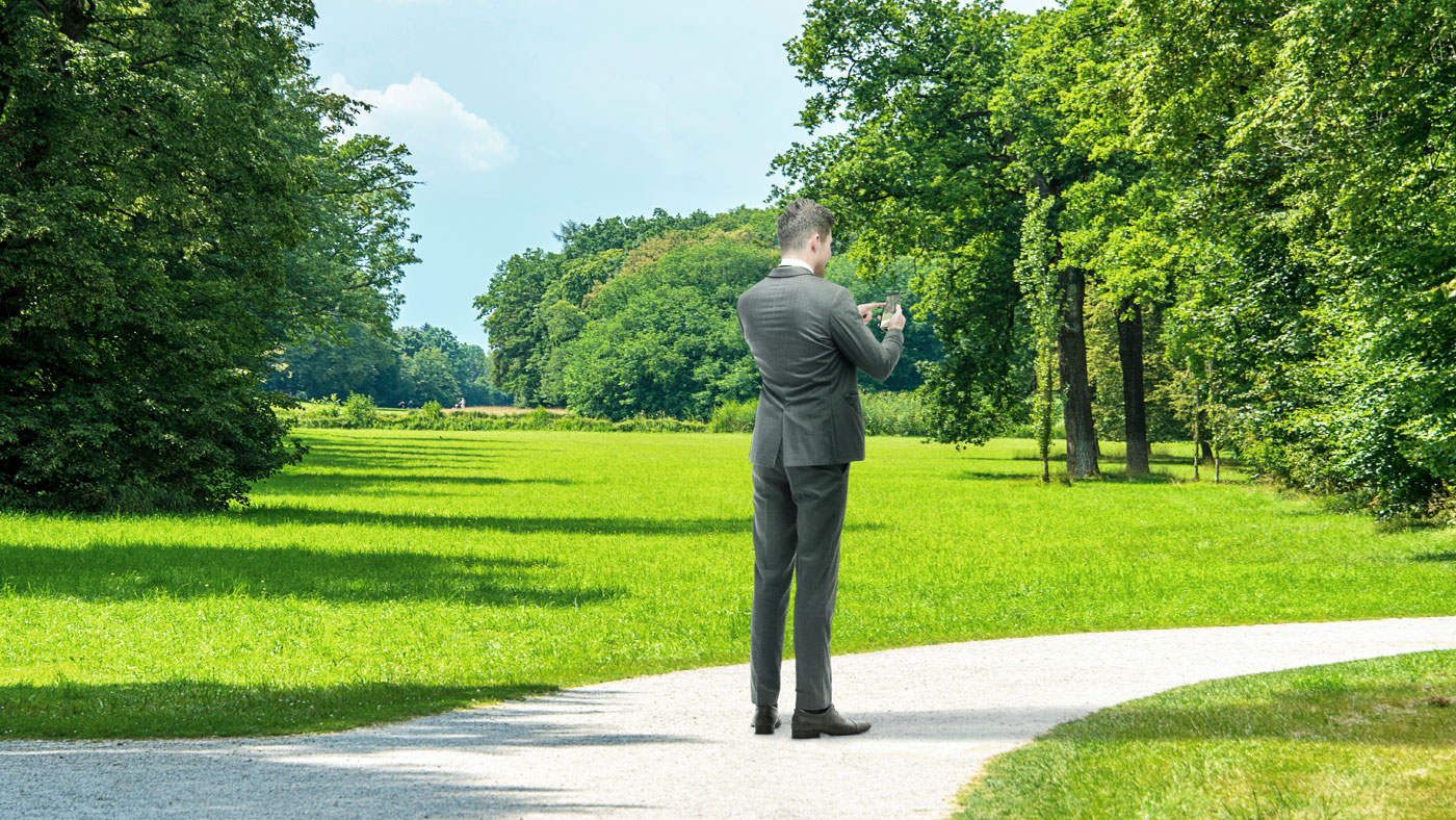 Geschäftsmann mit Telefon im Freien in einem grünen Park