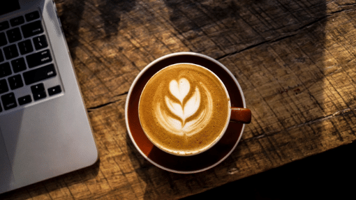 Cup of coffee with a laptop on wood table