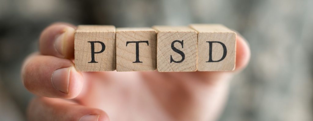 Hand holding letter blocks spelling PTSD