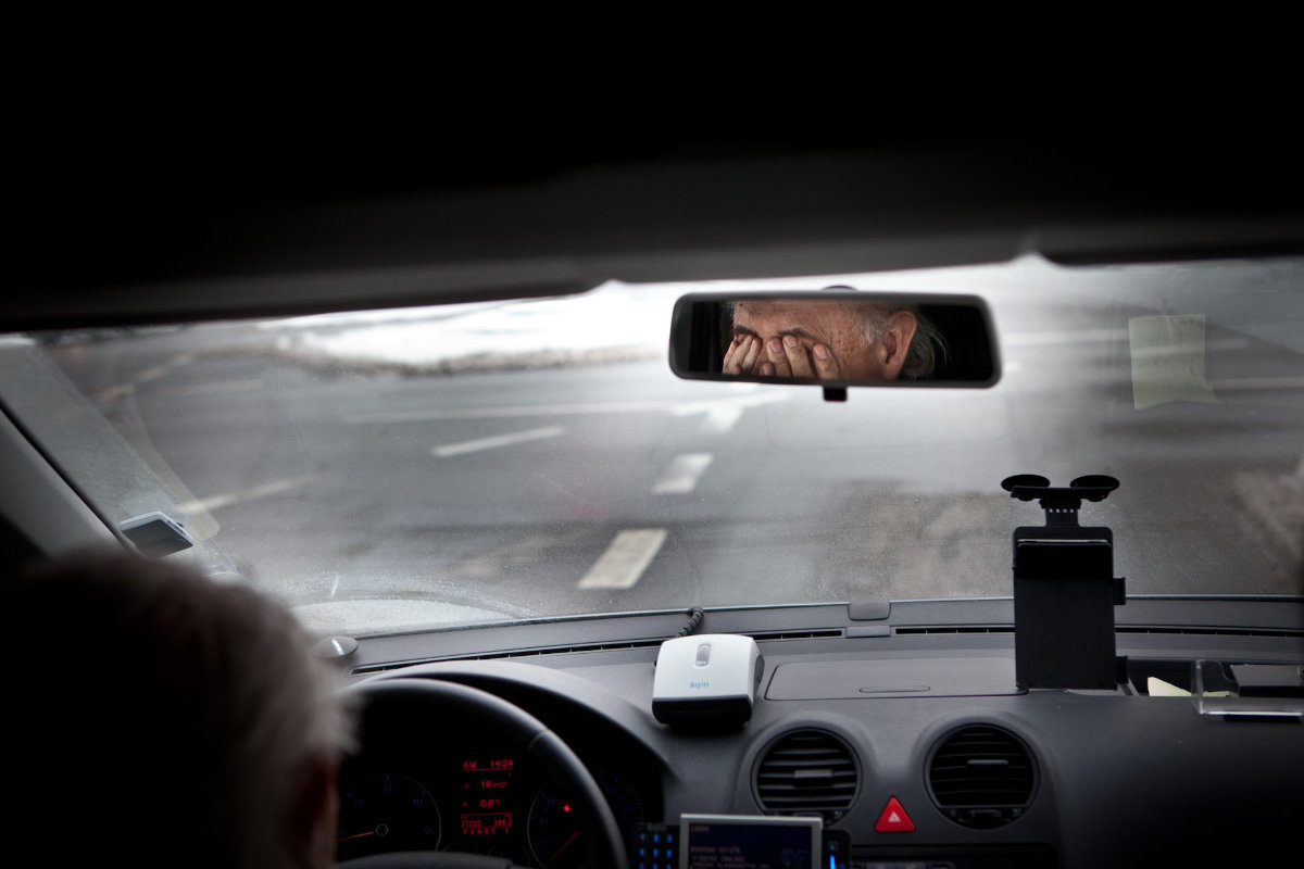 Man pressing his hands against his eyes inside a car. 