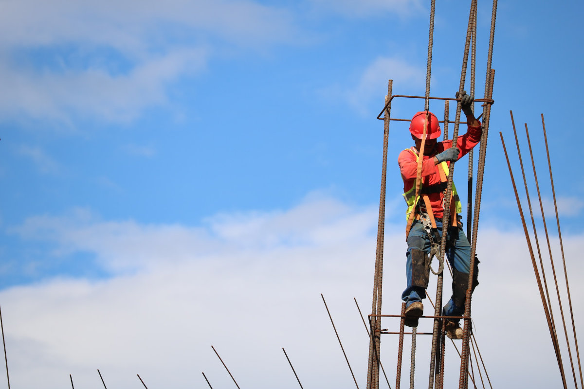 Trabajador de la construcción colgando de barras metálicas. 