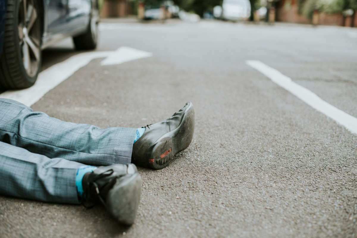 Primer plano de las piernas de un peatón tendido en la calle tras un accidente. 