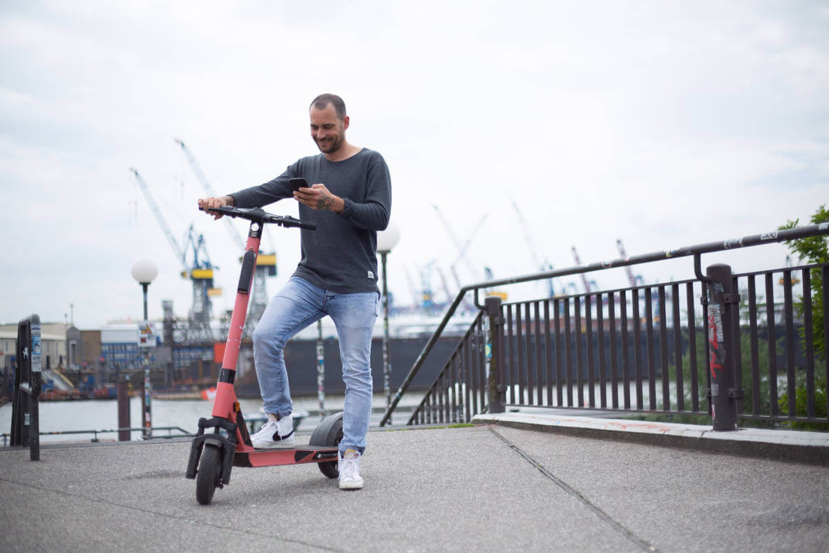 Man on his e-scooter checking his phone while stationary.